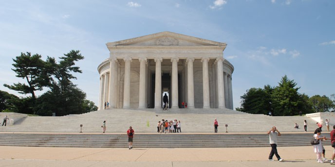 White Roman architectural style building with people on stairs and in plaza area