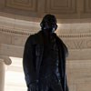 Bronze statue of man in chamber area with sunlight behind