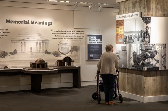 A visitor using a walker looks at photos and text in an exhibit.
