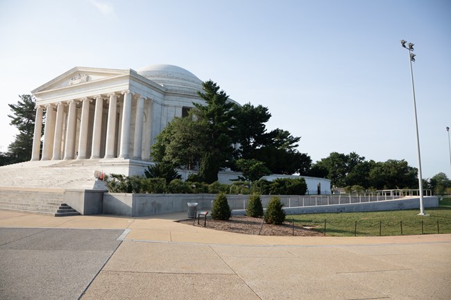 A large paved area in front of a ramp and stairs leading up to a large marble structure with columns.