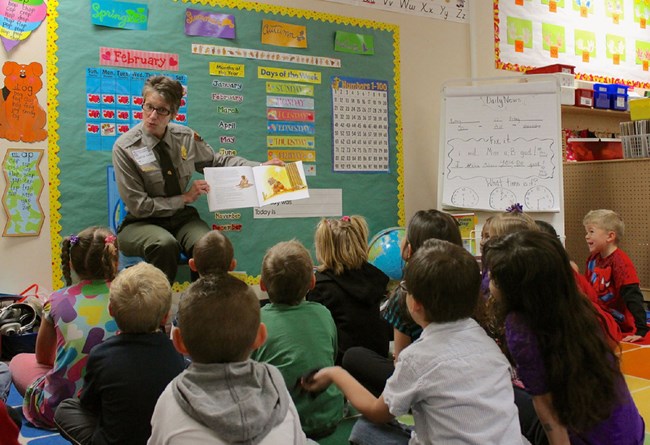 image of ranger reading a book to students in the classroom
