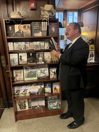 A man dressed as Theodore Roosevelt is browsing a bookstore.