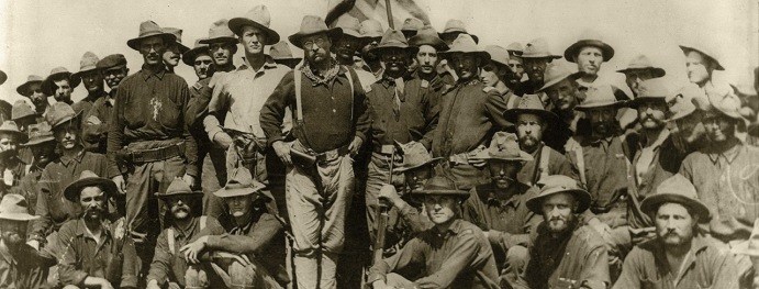 Sepia photo of the volunteer regiment Rough riders. A group of soldiers, with Colonel Roosevelt in the front center of image.