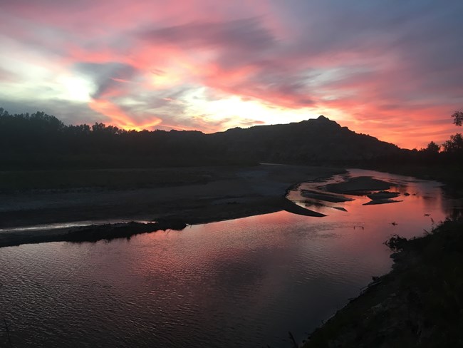The Little Missouri River under a pink and orange sky.