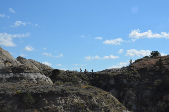 Three hikers on a ridge of the Caprock Coulee Trail in the North Unit.