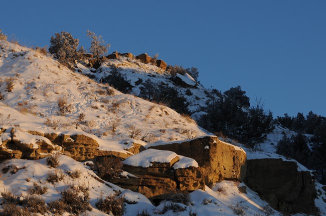 A snow-covered butte half in shadow.