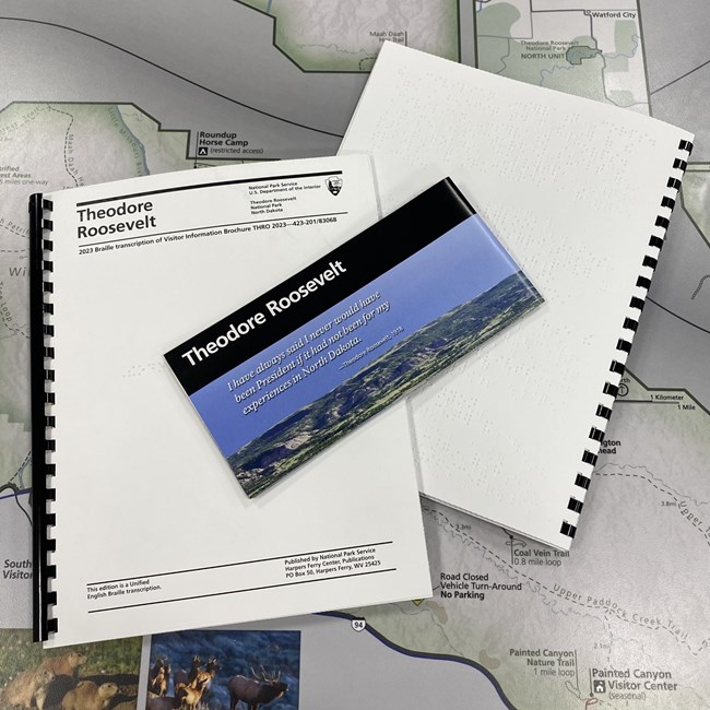 A standard copy of the Theodore Roosevelt National Park brochure, along with two braille transcriptions.