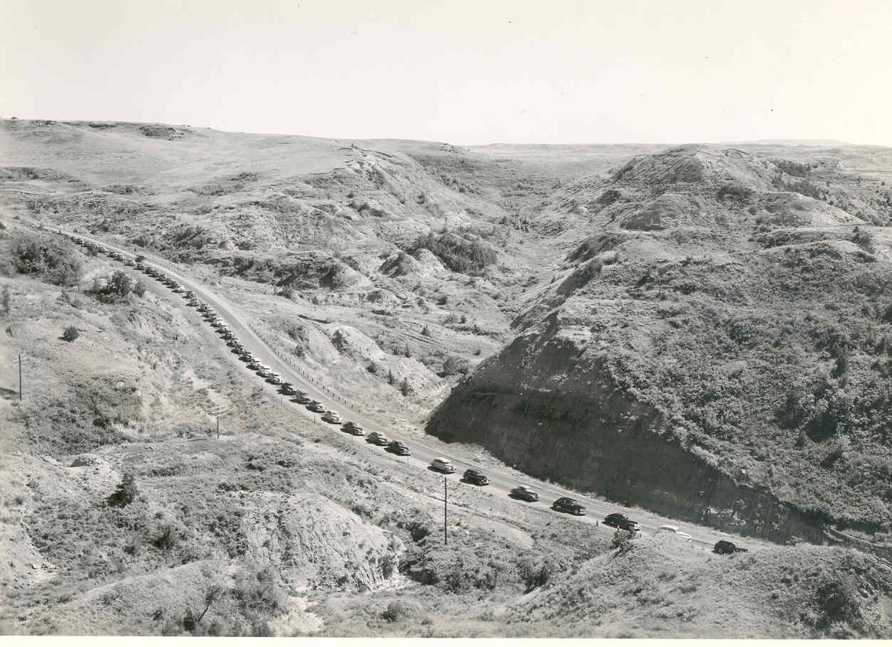Historic line of cars driving through Theodore Roosevelt National Park badlands scenic drive