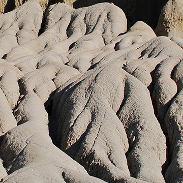 small crevasses cascading down a sandy outcropping show evidence of water erosion
