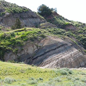 A mound of earth with diagonal rock layers