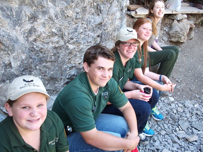 Youth volunteers sitting on a bench and smiling for the camera