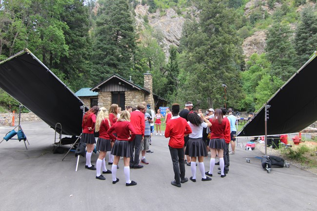 Teenagers standing in a parking lot surrounded by music video sets
