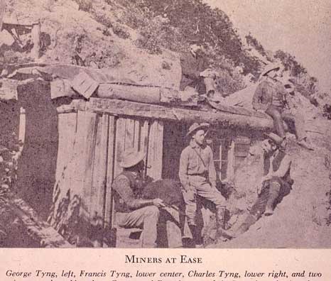 George Tyng sitting on top of the rustic log cabin on Miller Hill with Francis and Charles below with CH Joy sitting on the roof with his legs crossed.