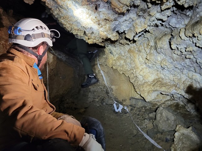 Visitor watches as a leg emerges from a cave passage
