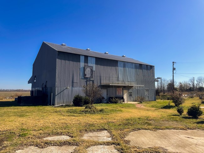 A metal cotton gin building in a field