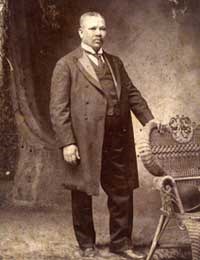 Portrait of Albert Sammis standing with hand resting on chair