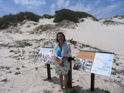 Graphic design intern Ximena Vergara stands at the sand dune with the exhibit panels she designed.