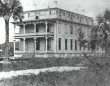 Image of Fort George Hotel. Sand, vegetation, and palm trees are also pictured.