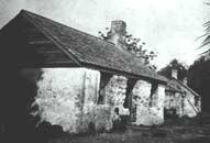 Historic photograph of two children standing outside slave cabin.