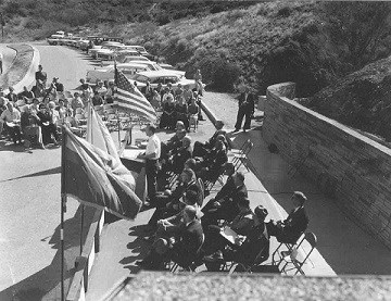 Black and white photograph of crowd sitting next to the new stone visitor center.