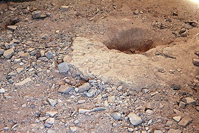 Original fire pit surrounded by dirt floor.