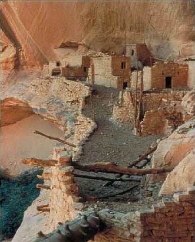 Photo of multiroom cliff dwelling with wooden beams.