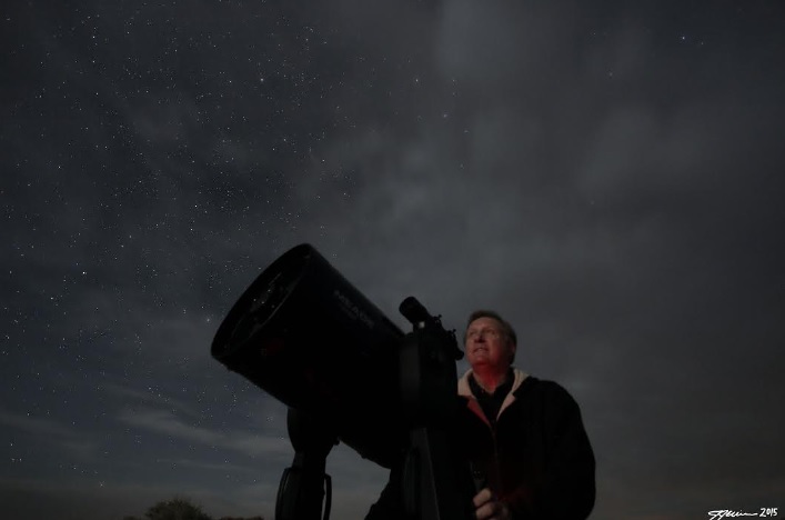 Dr. Larry Behers looks through a telescope