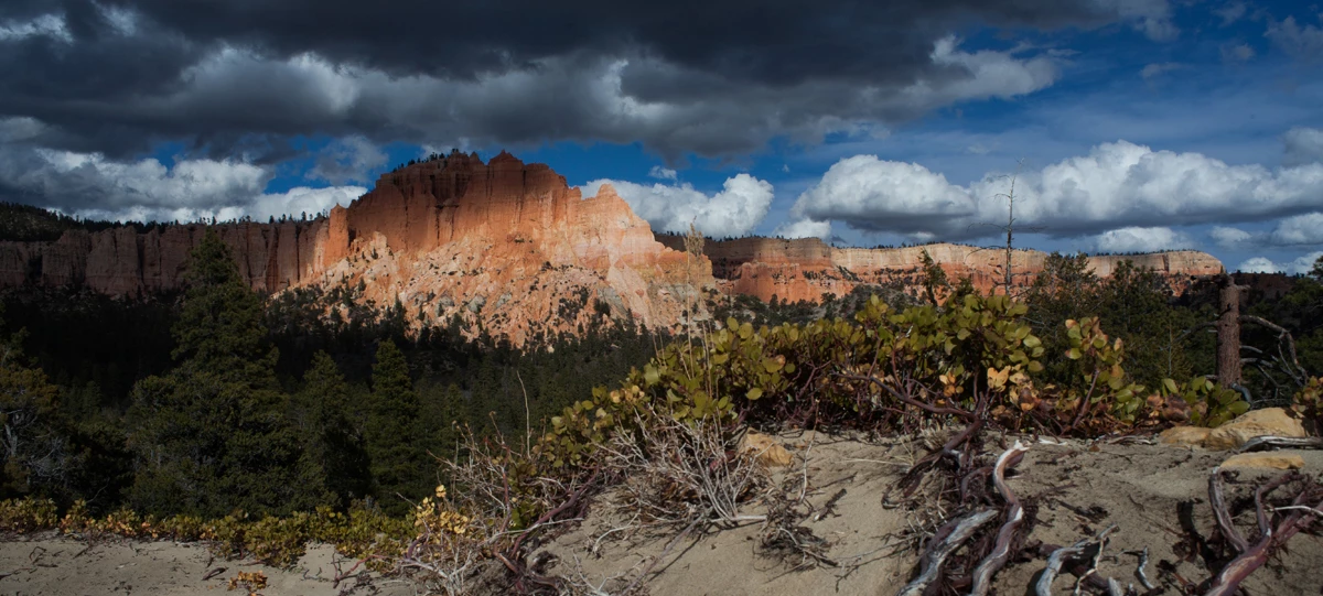 Outside the Bryce Amphitheater A large land formation with irregular red rock structures under dark storm clouds