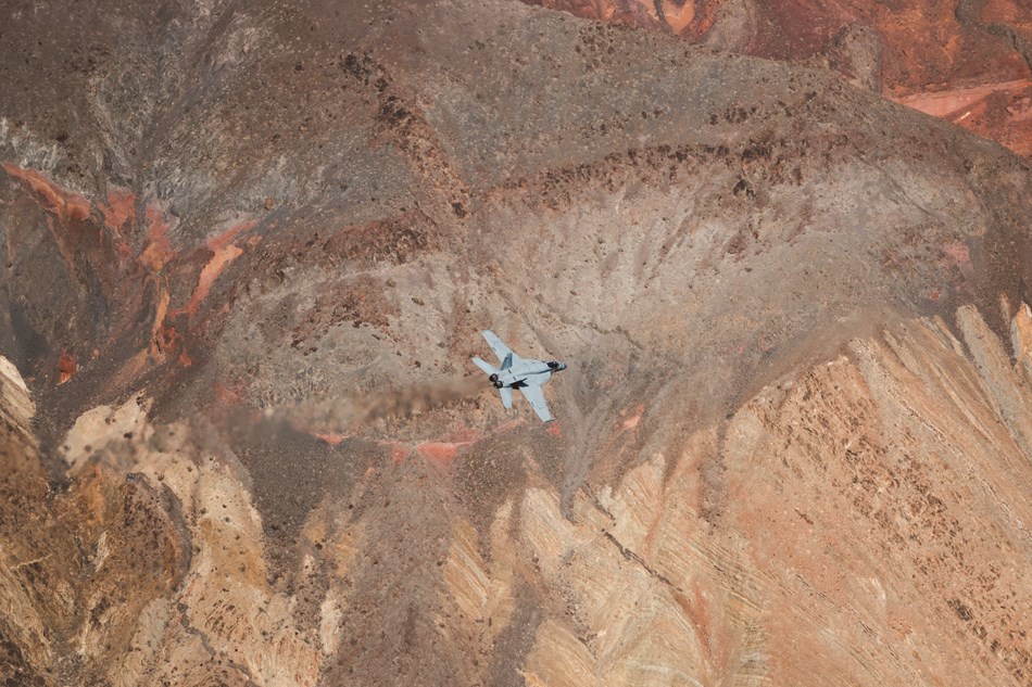 A jet fighter plane flies through a rainbow colored canyon. A jet fighter plane flies through a rainbow colored canyon.