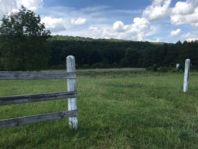 lt= A grassy field surrounded by a white picket fence.