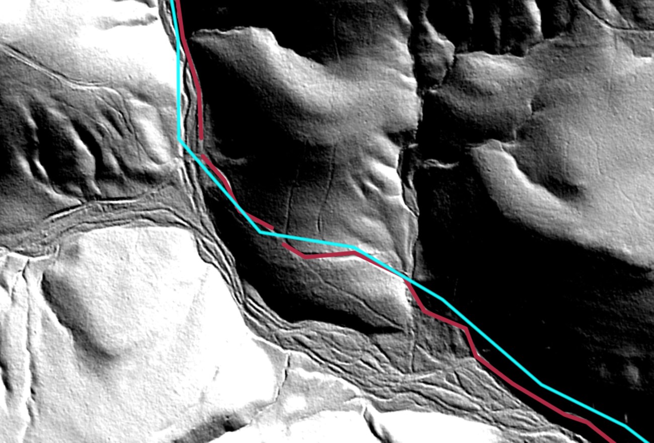 A shaded aerial image of rounded hills, depicting a trail through a canyon.
