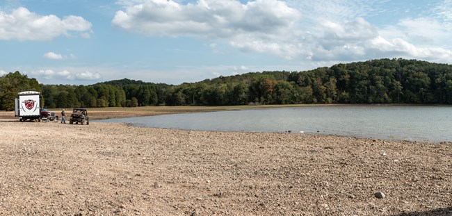 lt= An RV sits along the shore of a lake.