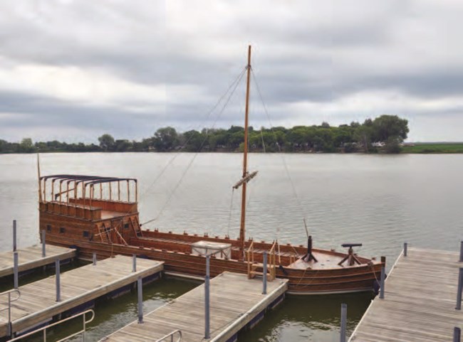 A keelboat at a dock on the river.