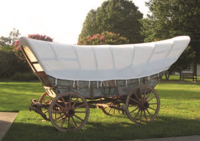 A large wooden, covered wagon.