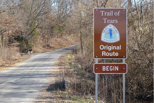 A brown sign indicating the Trail of Tears, next to a trail.