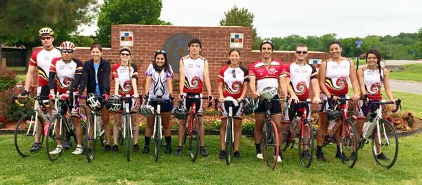 bicyclists in front of a brick facade, green grass