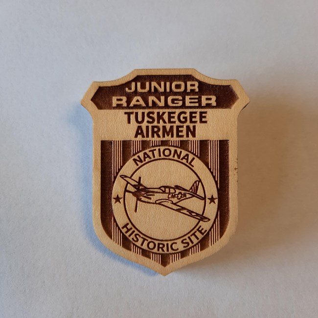 Wooden Junior Ranger badge reading Tuskegee Airmen National Historic Site