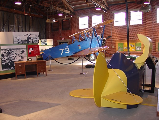 Restored Link Trainer Colored photo of the back of the Link Trainer with Plane in background