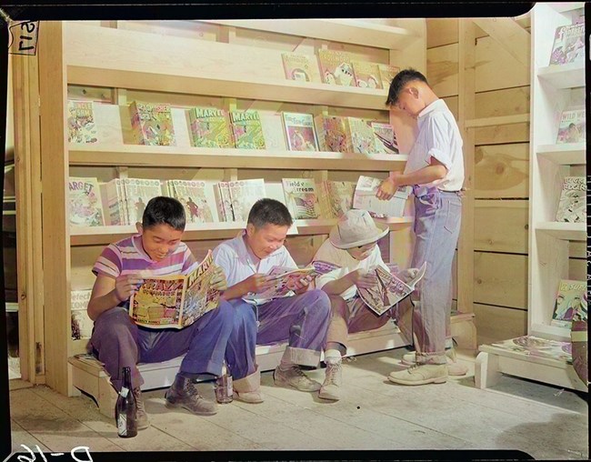 Four little evacuees from Sacramento, California, read comic books in the newstand at this War Relocation Authority center for evacuees of Japanese descent COLOR