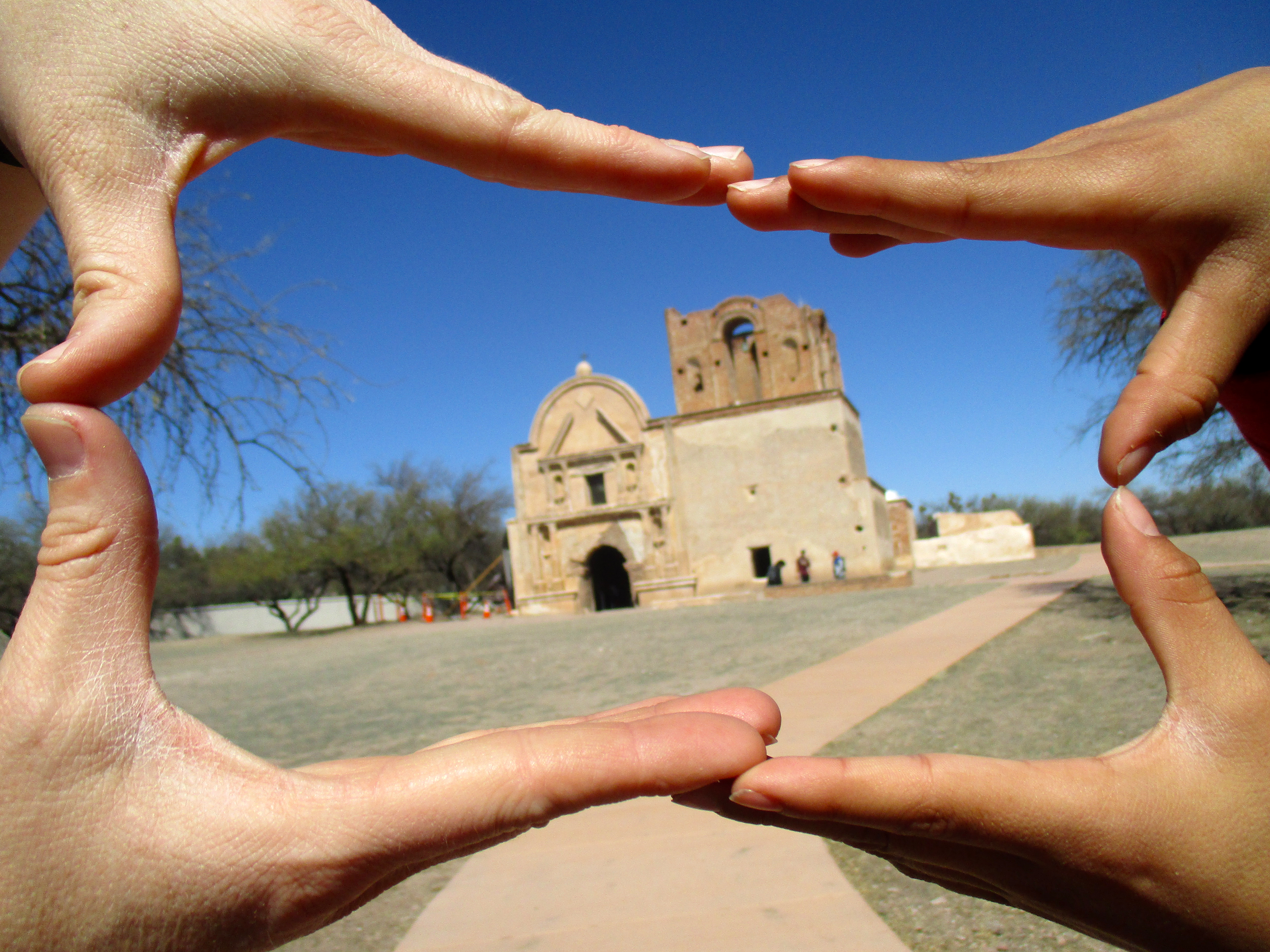 Color photograph of hands making a frame shape with church inside the frame.