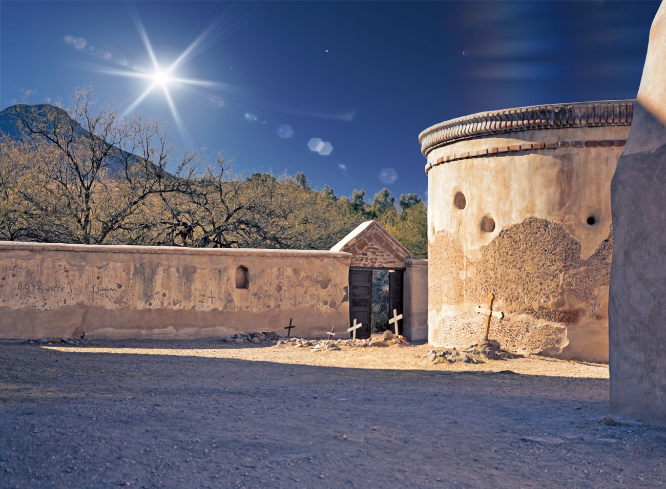 Photograph of adobe mortuary chapel with light from sun all around.
