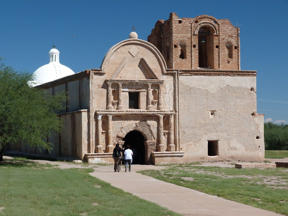 two women walking toward church on paved path two women walking toward church on paved path