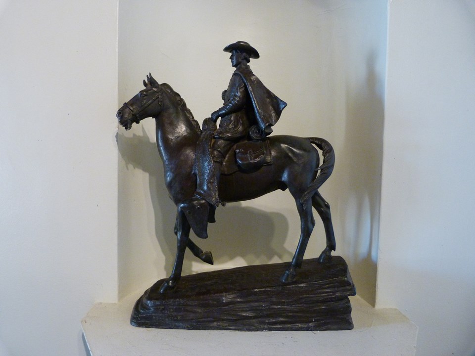 bronze statue of horseback padre in niche, on pedestal