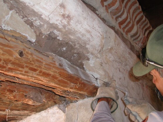 preservationist uses small trowel to apply plaster to edge of new wooden window casing