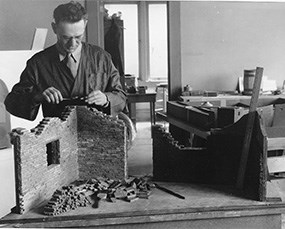 historic photo of man sculpting broken brick wall for diorama