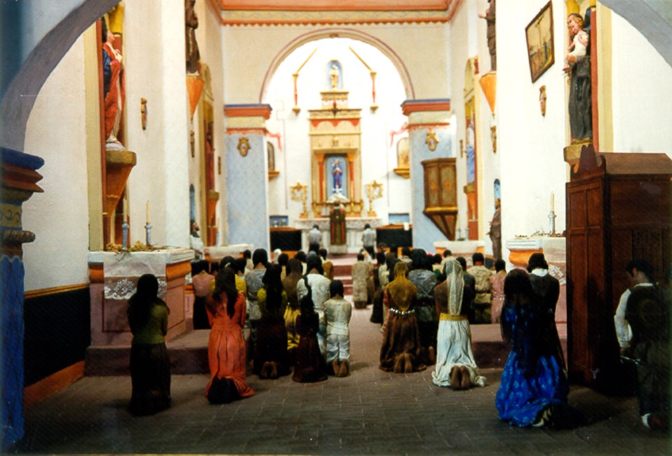 diorama of figures kneeling in highly decorated church interior