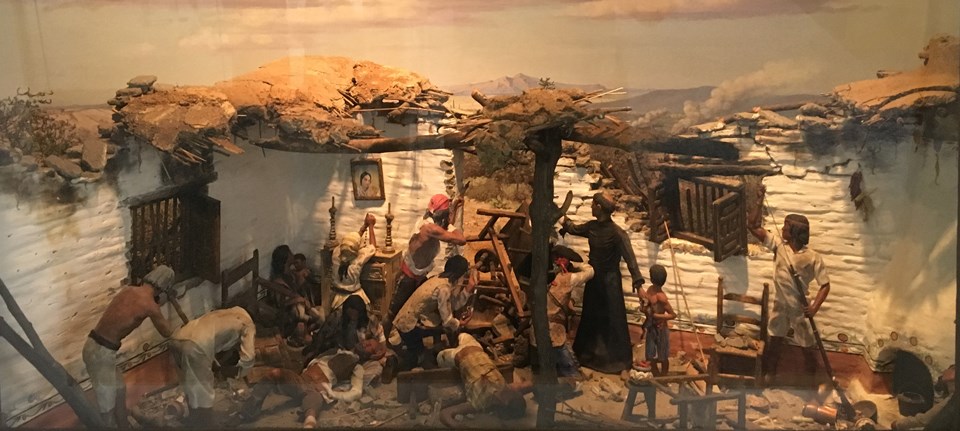diorama of battle scene with priest, native people, and spanish