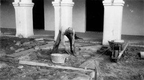 man laying bricks in herringbone pattern in front of arched walkway