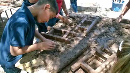 boy putting mud in adobe form