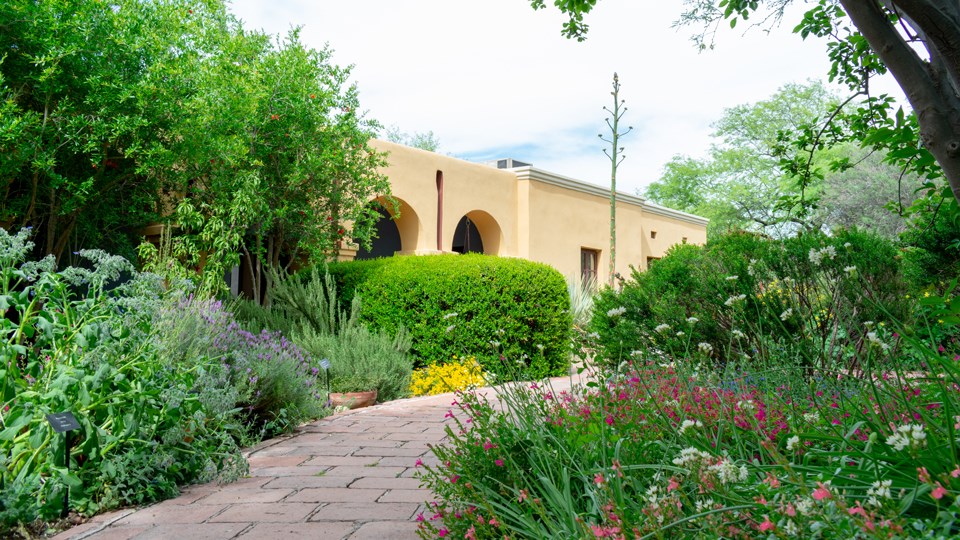 brick path lined with blooming multi-colored flowers and arched walkway